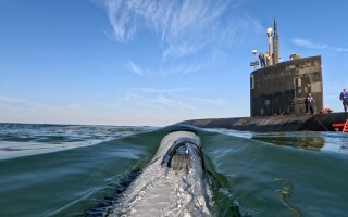 A small UUV approaches the USS Hampton submarine. U.S. Navy photo.