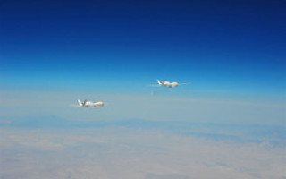 Two Global Hawk UAVs fly and refuel in close formation as part of DARPA program