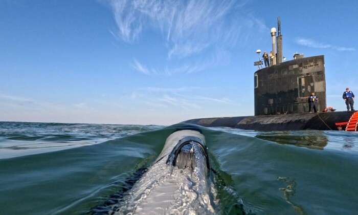 A small UUV approaches the USS Hampton submarine. U.S. Navy photo.